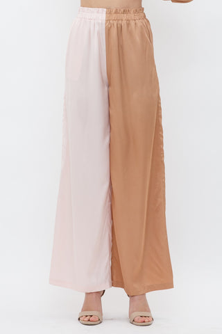 Model is standing in front of white backdrop. She is wearing a satin long sleeve top and satin pant set. The top is a color block satin top with one side peach and one side light pink. The pants are a color block satin pant with one side peach and the other side light pink. The photo is of the pants only.