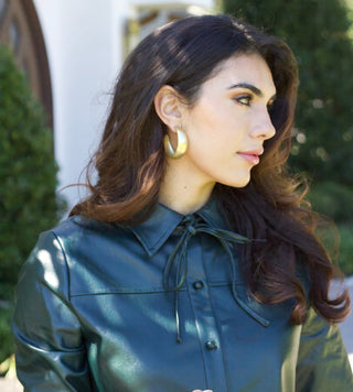 Model is wearing deep green vegan leather dress with drop waist, high collar and long sleeves. Photo is close up to show the detail of the collar and leather. 