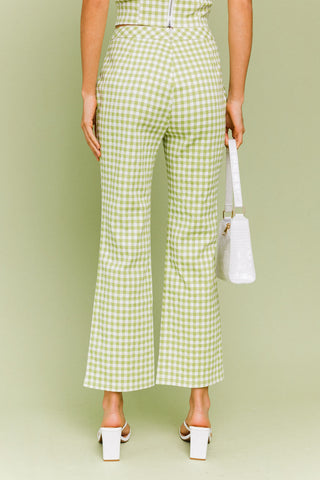 Model wearing a green and white gingham matching set. The top is a gingham corset, tube top. The pants are a straight leg, cropped gingham pant.  Model is standing in front of green background. Photo of the back of the pant. 