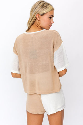 Model wearing tan and cream knit set. Model standing faced away from the camera.