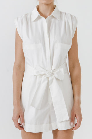 Model wearing white, collared, cotton, belted romper. She is standing in front of a white backdrop. The front of the romper is showing. 