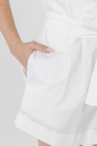 Image is up close on the pocket of a romper. The models hand is halfway into the pocket.